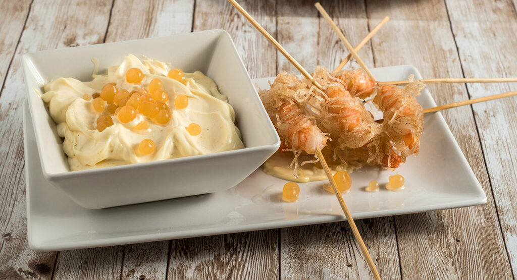 Langostinos envueltos en fideos de arroz con mayonesa de curry y falso caviar