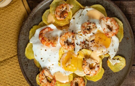 Huevos rotos con gambones al ajillo